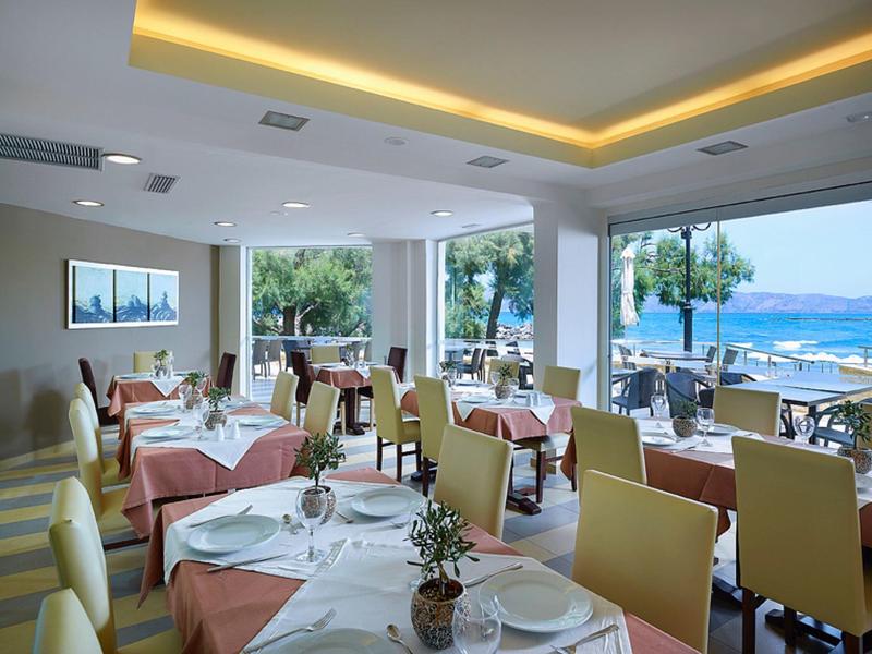 Elegant ingericht restaurant met zeezicht en tafels gedekt met witte tafelkleden.