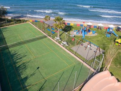 Blick auf Tennisplatz und Spielplatz am Strand mit Meer im Hintergrund.