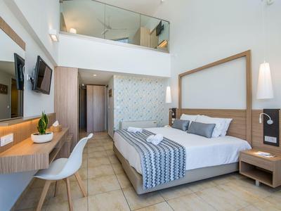 Nowoczesny pokój hotelowy z łóżkiem podwójnym, telewizorem z płaskim ekranem i biurkiem w jasnym wystroju.