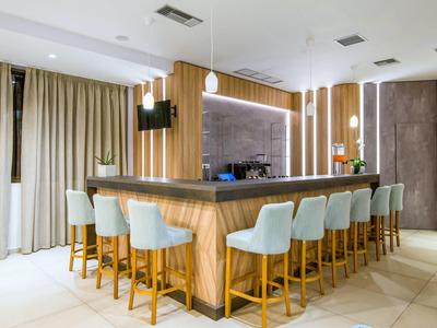 Moderní hotelový bar s dřevěnými pulty a světle modrými polstrovanými stoličkami.