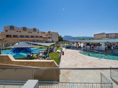 Große Hotelanlage mit Pool, Sonnenschirmen und Bergblick unter klarem Himmel.