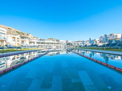 Großer Hotelpool unter klarem blauem Himmel mit reflektierenden Gebäuden.