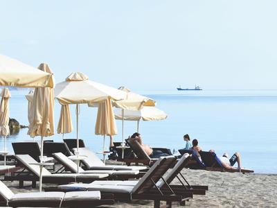 Prázdná lehátka a slunečníky na klidné pláži s výhledem na moře.