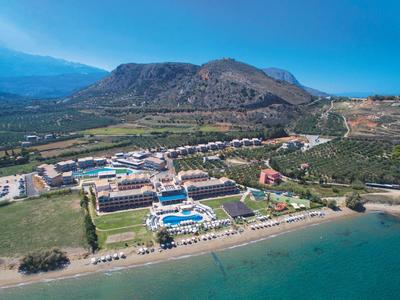 Resort s bazénem a pláží poblíž hory pod jasně modrou oblohou.