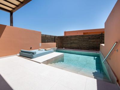 Malý venkovní bazén se světle modrou vodou, obklopený broskvovými zdmi a bílými dlaždicemi.