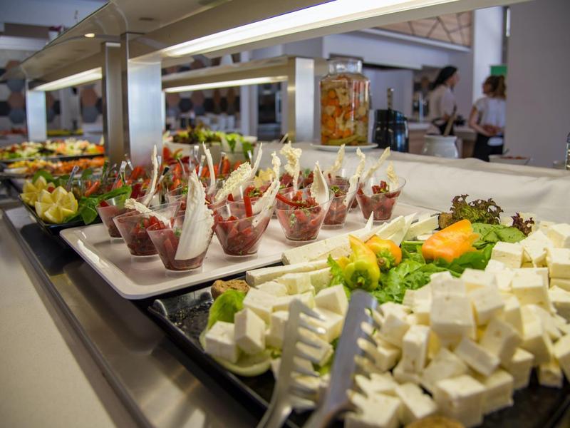 Bufet s čerstvým sýrem, ovocem a předkrmy na tácích.