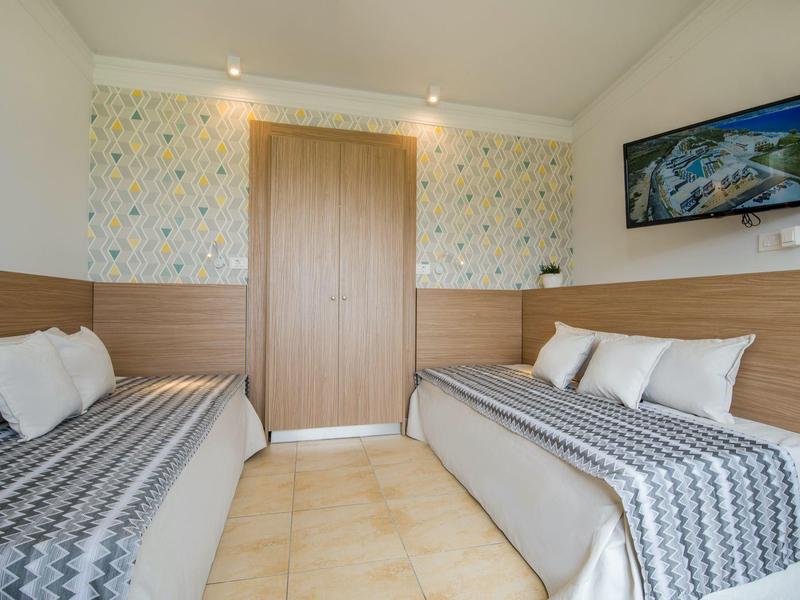 Deux lits modernes avec des couvertures à motifs dans une chambre d'hôtel lumineuse avec des accents en bois.