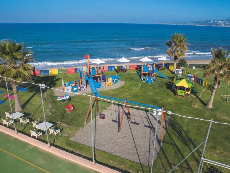 Hřiště u pláže s houpačkami, skluzavkami a palmami poblíž oceánu