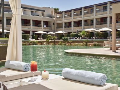 Poolbereich eines modernen Hotels mit Liegen, Sonnenschirmen und Getränken am Beckenrand.