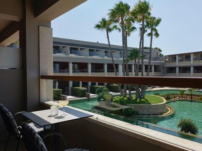 Blick von einem Balkon auf einen Hotelinnenhof mit Pool und Palmen.