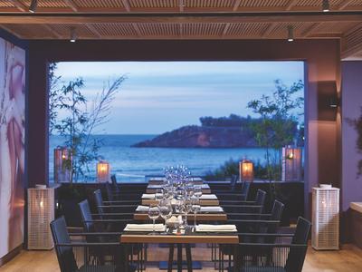 Elegantes Restaurant mit Meerblick, gedeckten Tischen und modernem Design.