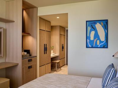 Modernes Hotelzimmer mit Holzschränken, Doppelbett und blauem Kunstwerk an der Wand.