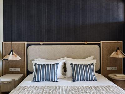 Modernes Hotelzimmer mit Doppelbett, gestreiften Kissen und zwei Nachttischen mit Lampen