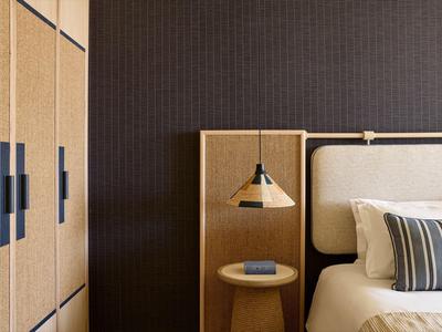 Modernes Schlafzimmer mit hellen Holzschränken, Nachttisch und Bett mit gestreiftem Kissen.