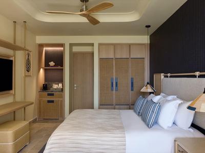 Modern eingerichtetes Hotelzimmer mit großem Bett, Holzmöbeln und Blick auf Fernseher.