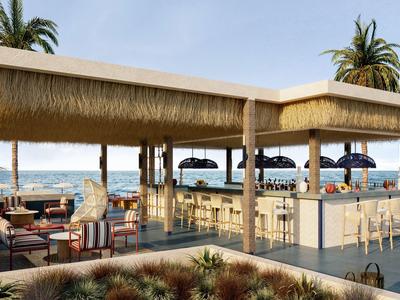 Bar abierto con asientos y vista al mar bajo un cielo despejado.