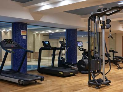 Moderner Fitnessraum mit Laufbändern, Fitnessgeräten und Holzboden in einem Hotel.