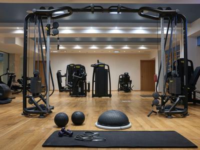 Moderner Fitnessraum mit Trainingsgeräten, Matte, Medizinbällen und Holzfußboden.