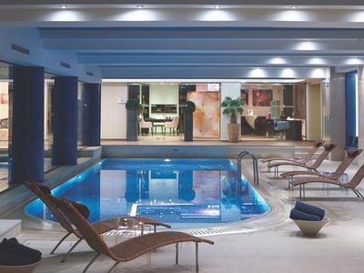 Innenpool in modernem Wellnessbereich mit Liegestühlen und gedämpfter Beleuchtung.