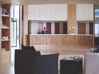 Moderner Hotel-Lobbybereich mit Empfangstresen und Sitzgelegenheiten in warmen Farbtönen.