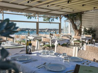 Offenes Restaurant mit gedeckten Tischen und Blick auf das Meer bei Tageslicht.