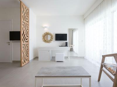 Helles Hotelzimmer mit modernem Schreibtisch, Stuhl und großem Fenster mit Vorhängen.