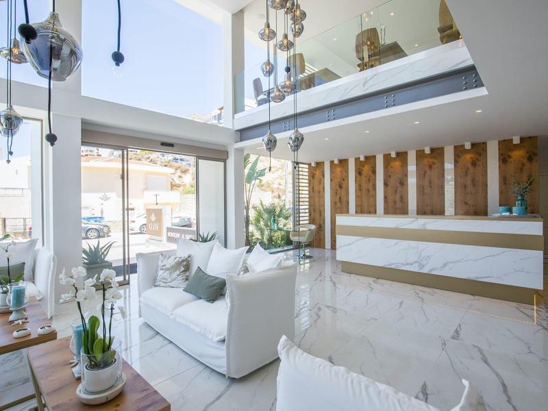 Helles Wohnzimmer mit großen Fenstern, weißen Sofas, grünen Pflanzen und modernen Akzenten.