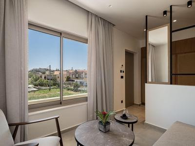 Modernes Hotelzimmer mit großem Fenster und Blick auf eine Stadtlandschaft bei klarem Himmel.