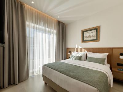 Modernes Hotelzimmer mit Doppelbett, grün-weißem Bettzeug und Vorhängen am Fenster.