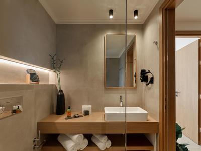 Modernes Badezimmer mit Waschbecken auf Holztisch und Spiegel an grauer Wand.