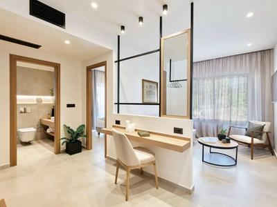 Modern eingerichtetes Hotelzimmer mit Schreibtisch, Sitzecke und Blick ins Badezimmer.