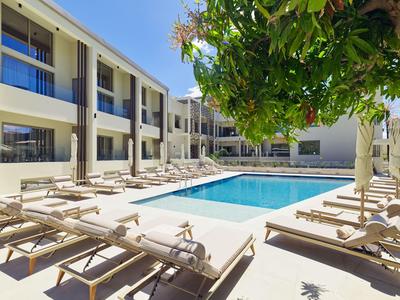 Moderner Hotelpool mit Liegestühlen und Sonnenschirmen unter blauem Himmel.