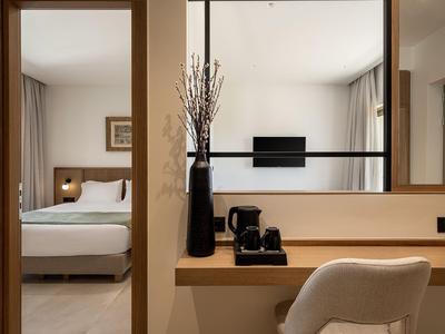 Modern eingerichtetes Hotelzimmer mit gemütlichem Bett, Schreibtisch und Fernseher an der Wand.