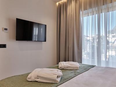 Hell eingerichtetes Hotelzimmer mit Bett, zwei gefalteten Handtüchern und großem Fenster mit Vorhängen.