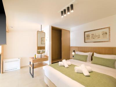 Hell eingerichtetes Hotelzimmer mit Doppelbett, Holzmöbeln und minimalistischer Dekoration.