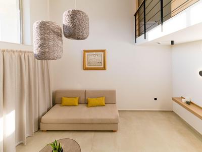 Modernes, helles Wohnzimmer mit Sofa, gelben Kissen und großen, runden Lampenschirmen.