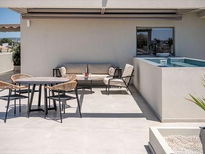Moderner Hotelbalkon mit Sitzbereich und kleinem Pool, heller Boden und klarer Himmel.
