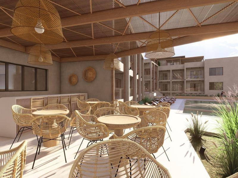 Moderner Außenbereich mit geflochtenen Stühlen, Tischen und Holzdach, umgeben von Gebäuden.