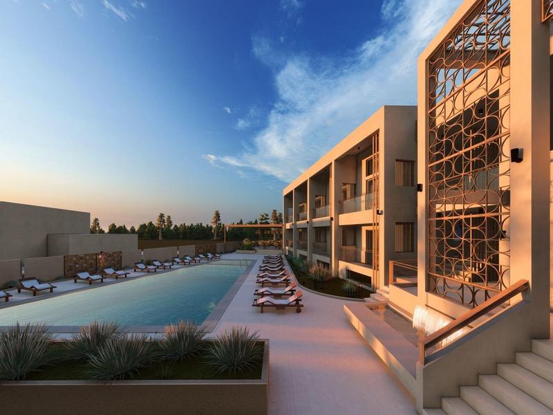 Moderner Hotelpool bei Sonnenuntergang mit Sonnenliegen und mehrstöckigem Gebäude aus Glas und Beton.