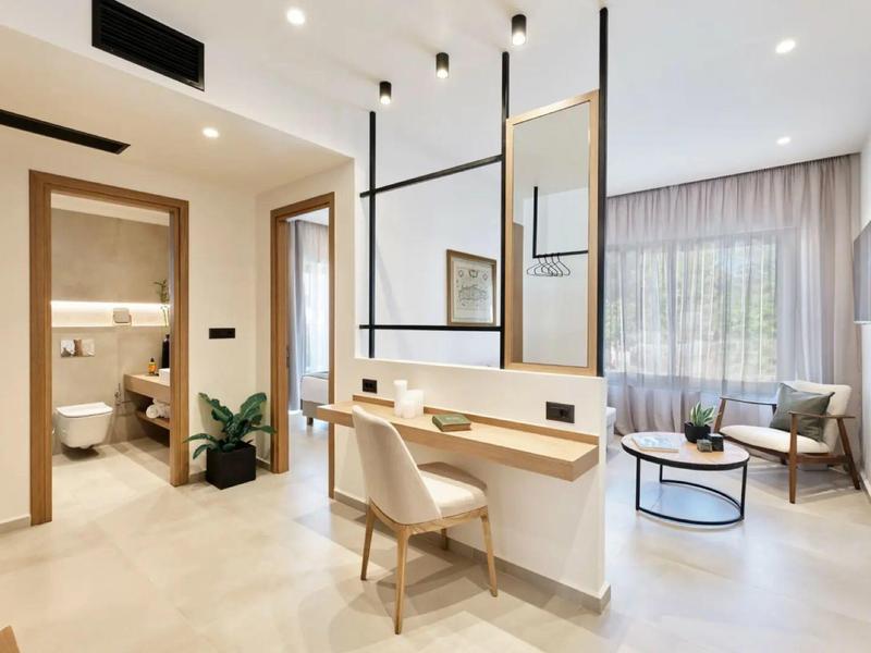 Modern eingerichtetes Hotelzimmer mit Schreibtisch, Sitzecke und Blick ins Badezimmer.