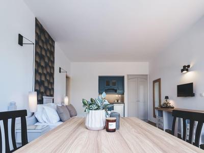 Modern interieur van hotelkamer met bed, tafel, stoelen en wanddecoratie in neutrale tinten.