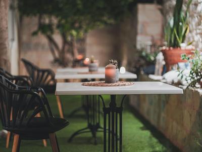 Bílý stůl s černou židlí a rostlinnou dekorací stojí před kavárnou.