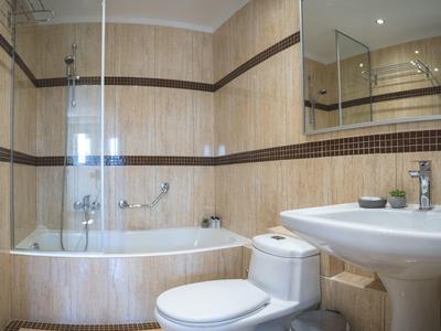 Moderne badkamer met bad, douche, toilet en wastafel in beige tinten.