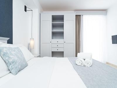 Lichte hotelkamer met groot bed, kast en tv, modern ingericht.