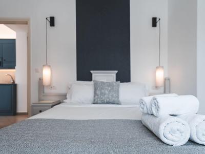 Moderne slaapkamer met grijs bed, witte muren en opgerolde handdoeken op het bed.