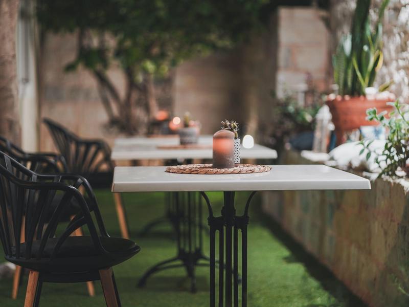 Gezellige tafel met stoelen in een tuinrestaurant met planten en zachte verlichting.