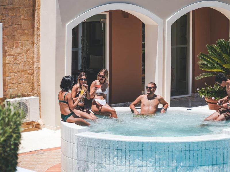 Een groep mensen ontspant in een ronde buitenzwembad naast een hotel.