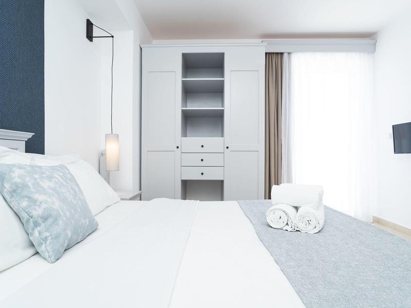 Lichte hotelkamer met groot bed, kast en tv, modern ingericht.