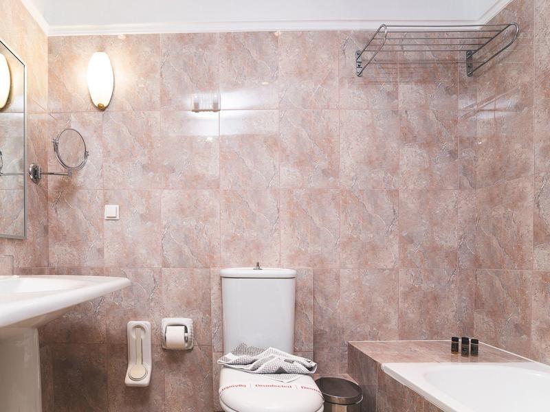 Eenvoudige badkamer met wastafel, toilet en bad in een hotelkamer.