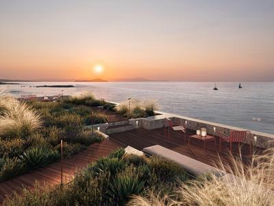 Sonnenuntergang über einem Strand mit Sanddünen und einer Holzterrasse mit Sitzgelegenheiten.